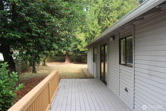 a view of a backyard with large tree and wooden fence