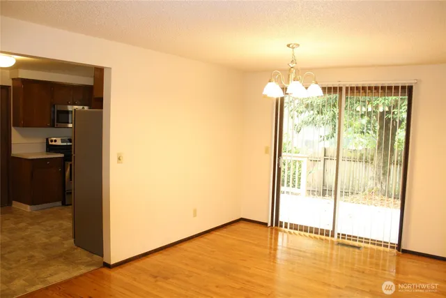 a view of an empty room with wooden floor and a fireplace