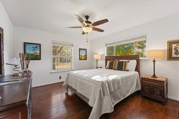 a bedroom with a bed and dresser with wooden floor