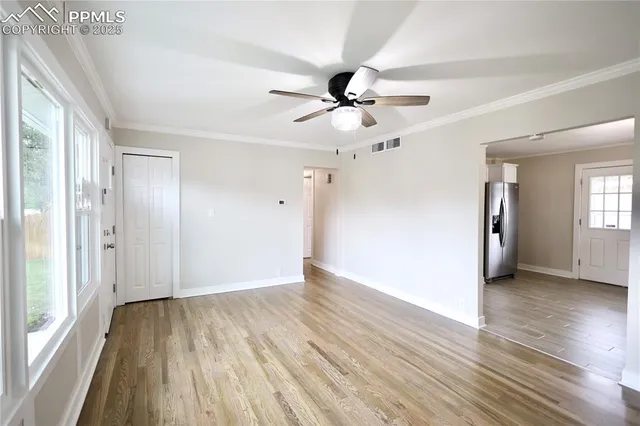 a view of empty room with wooden floor and fan