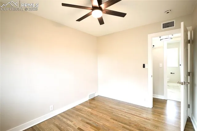a view of a hallway with wooden floor and a ceiling fan