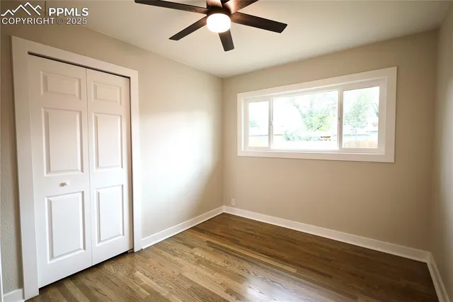 a view of empty room with wooden floor and fan