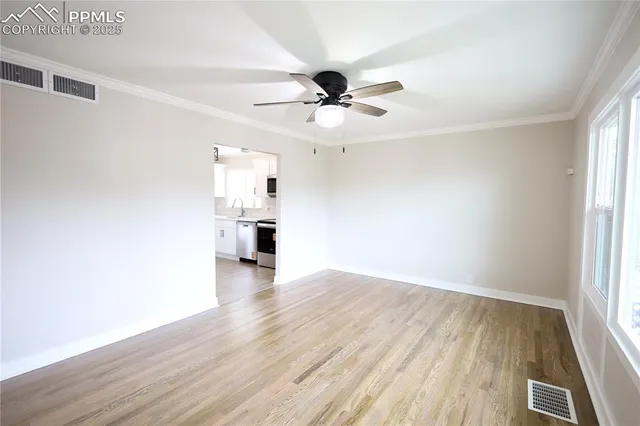 an empty room with wooden floor ceiling fan and windows