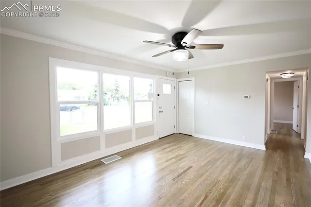 a view of empty room with wooden floor and fan
