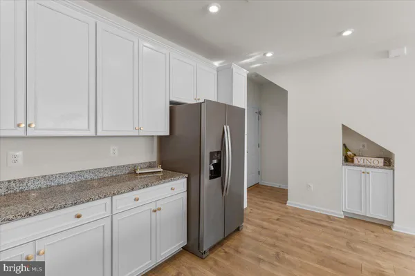 a kitchen with granite countertop white cabinets and refrigerator