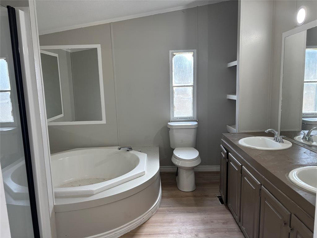 7431 Grubbs Road Aubrey, TX 76227 - Photo 7 of 17 Corner soaking tub, dual vanity with integrated sinks, built-in shelving, and wood-finish flooring
