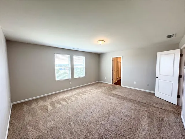 an empty room with windows and refrigerator