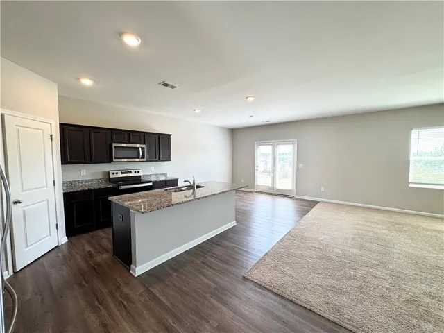 a large kitchen with cabinets wooden floor and stainless steel appliances