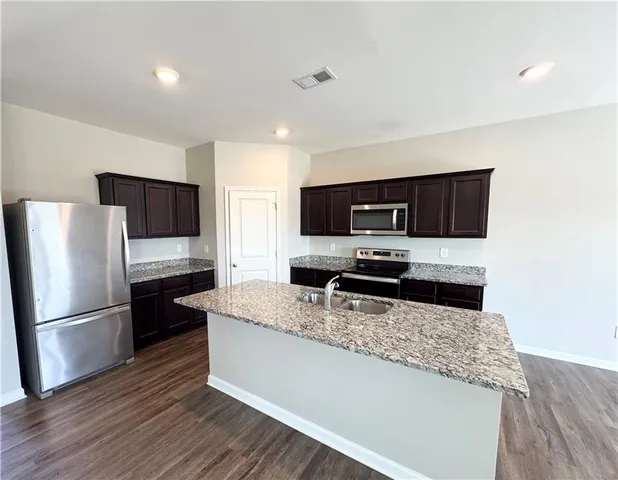 a kitchen with stainless steel appliances granite countertop a refrigerator and a stove top oven