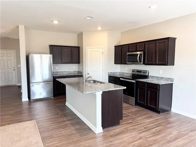 a large kitchen with stainless steel appliances wooden cabinets and a wooden floor