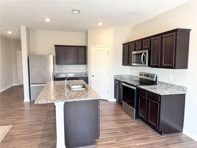 a kitchen with stainless steel appliances granite countertop a stove a sink and a microwave