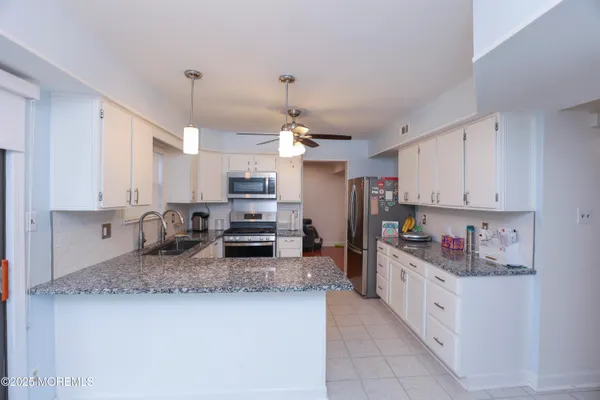a kitchen with kitchen island granite countertop stainless steel appliances a sink stove top oven and cabinets