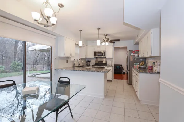 a kitchen with stainless steel appliances granite countertop a refrigerator a stove top oven a sink dishwasher a dining table and chairs with wooden floor