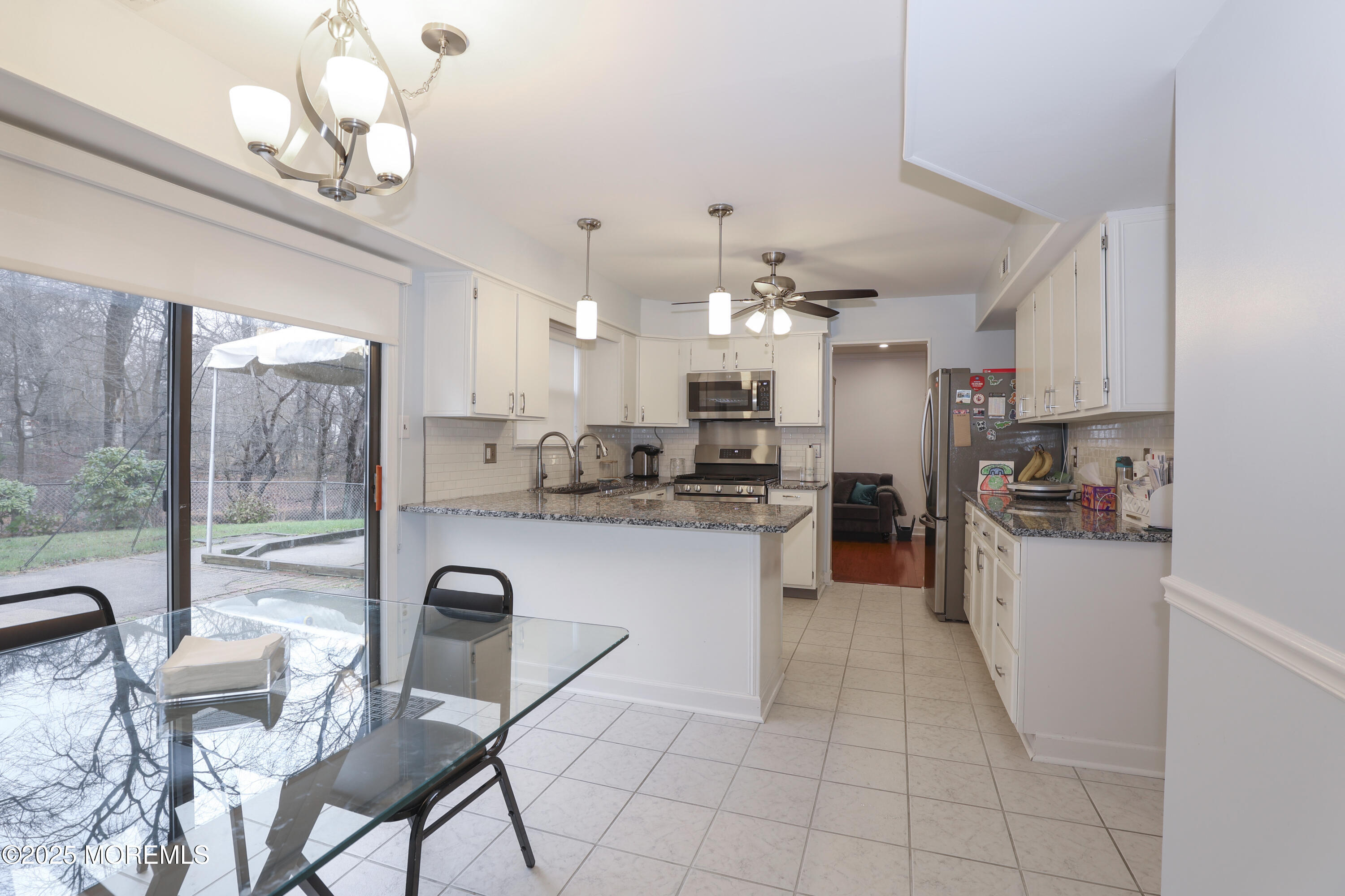 302 Princeton Drive Howell, NJ 07731 - Photo 14 of 30 a kitchen with stainless steel appliances granite countertop a refrigerator a stove top oven a sink dishwasher a dining table and chairs with wooden floor