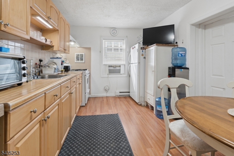61 Union Street, Unit 2 Lodi, NJ 07644 - Photo 3 of 8 a kitchen with furniture a flat screen tv and a refrigerator