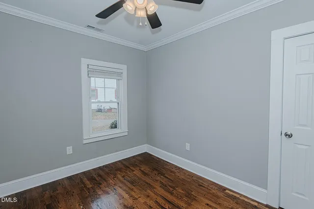 an empty room with wooden floor chandelier fan and windows