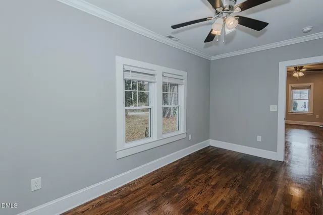 an empty room with wooden floor fan and windows