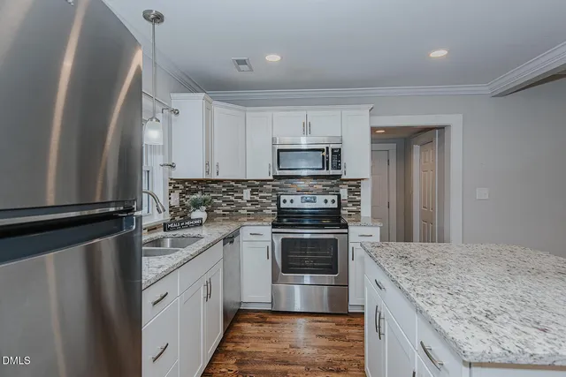 a kitchen with stainless steel appliances granite countertop a stove top oven a sink and a refrigerator