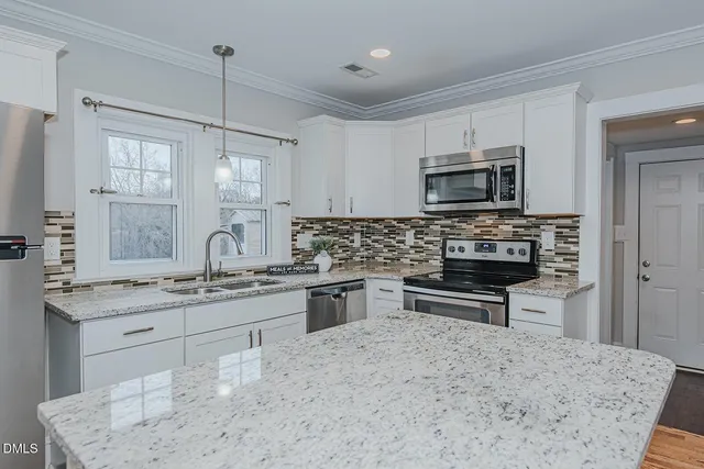 a kitchen with stainless steel appliances kitchen island granite countertop a sink stove and microwave