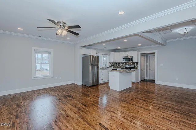 a view of kitchen with granite countertop stainless steel appliances cabinets a wooden floor and a window