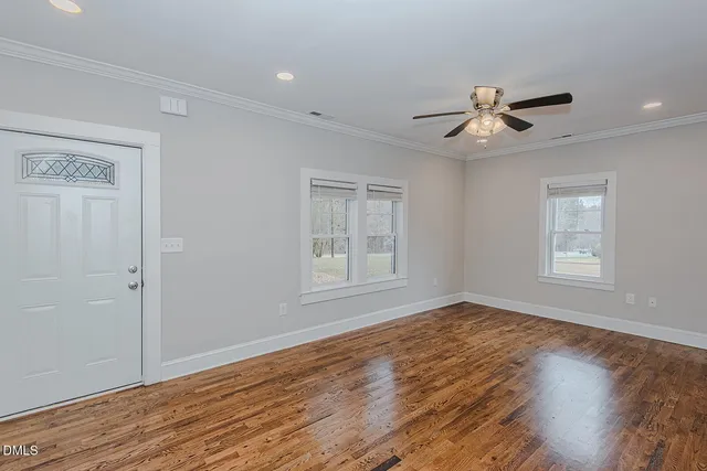 a view of empty room with wooden floor and fan