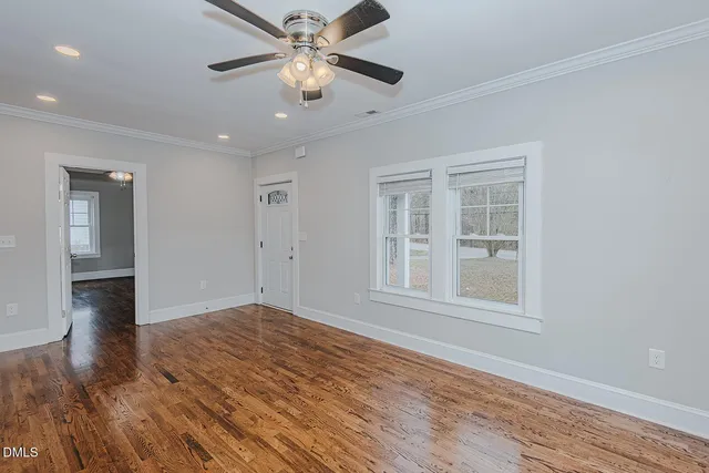 a view of empty room with wooden floor and fan