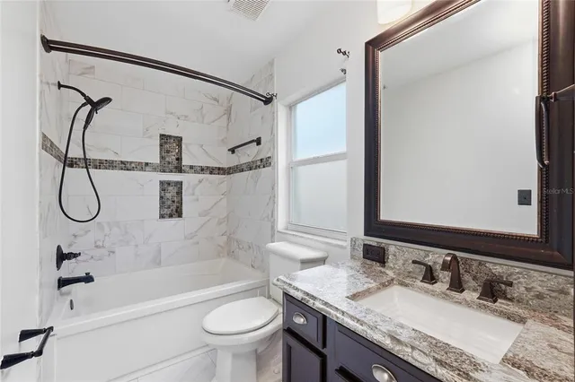 a bathroom with a granite countertop sink a toilet and a mirror
