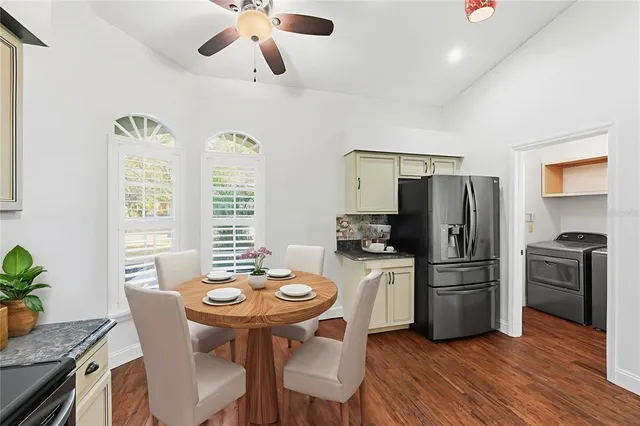 a kitchen with stainless steel appliances a dining table chairs and refrigerator