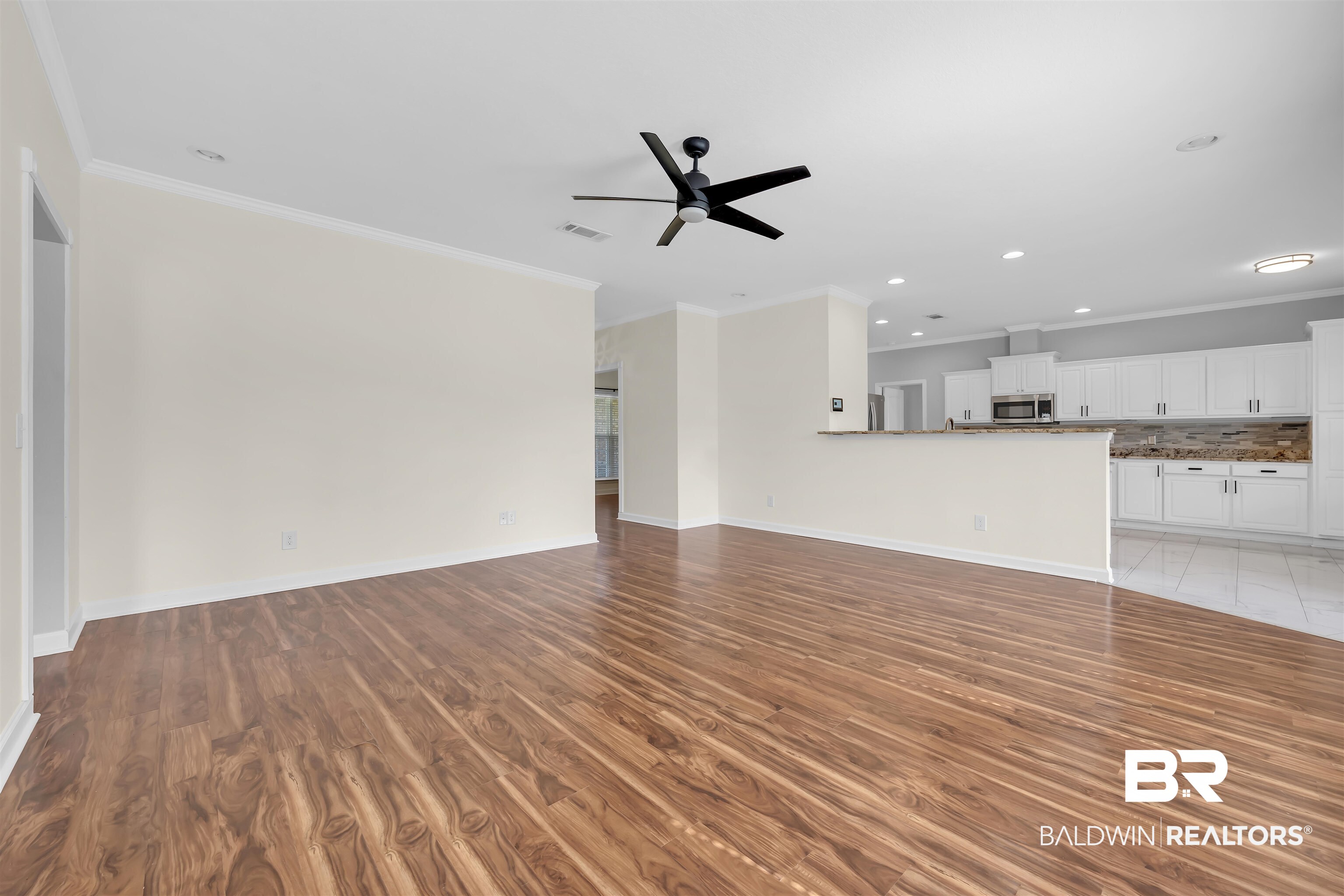10147 Lyttleton Loop Lillian, AL 36549 - Photo 14 of 29 Spacious living area featuring wood-finish flooring, a contemporary ceiling fan, and crown molding