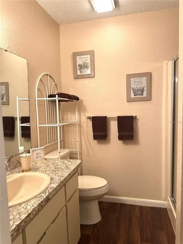 a bathroom with a granite countertop sink toilet a mirror and shower