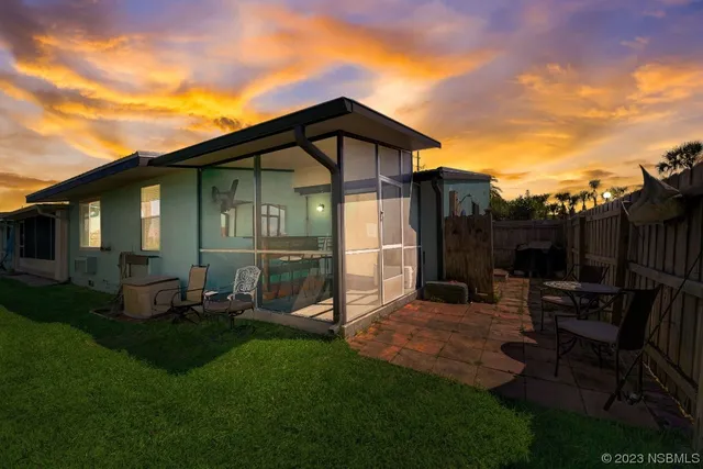 a view of a chair and table in backyard of the house