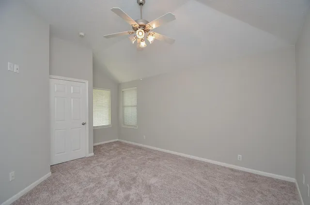 an empty room with a chandelier fan and windows