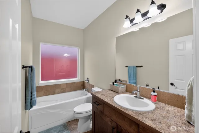 a bathroom with a granite countertop sink a toilet a mirror and shower
