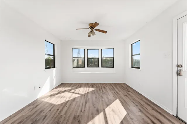 a view of empty room with wooden floor and ceiling fan