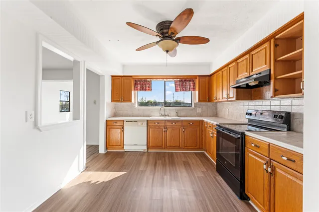 a kitchen with a wooden floor window and stainless steel appliances