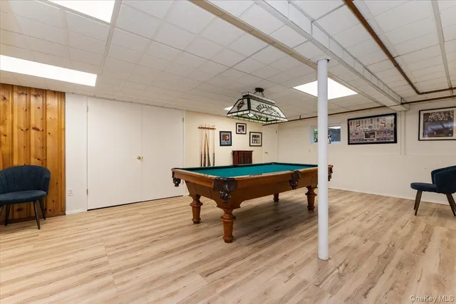 a room with wooden floor pool table and windows