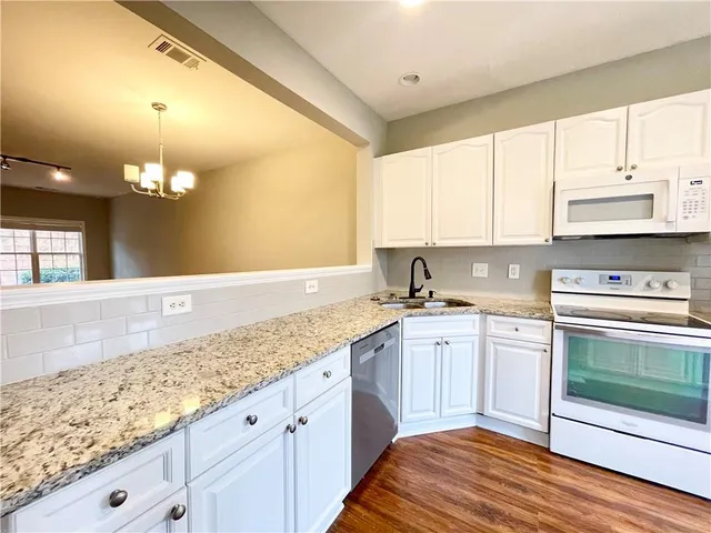 a kitchen with granite countertop a sink stainless steel appliances wooden floor and cabinets