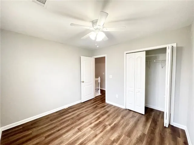 an empty room with wooden floor and fan