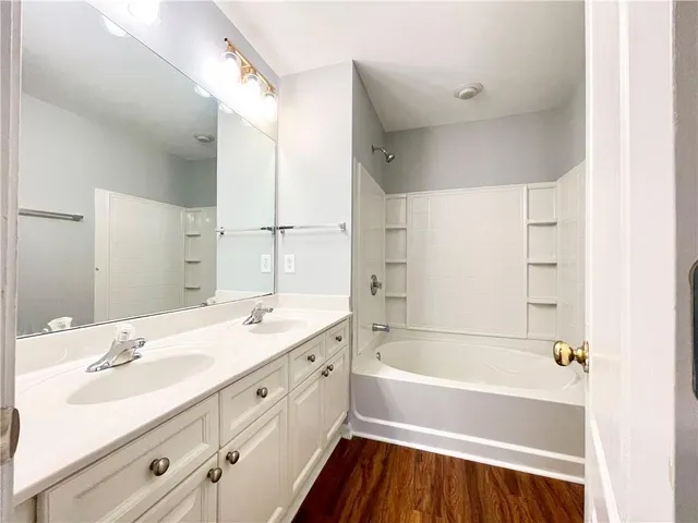 a bathroom with a tub sink double vanity and a mirror