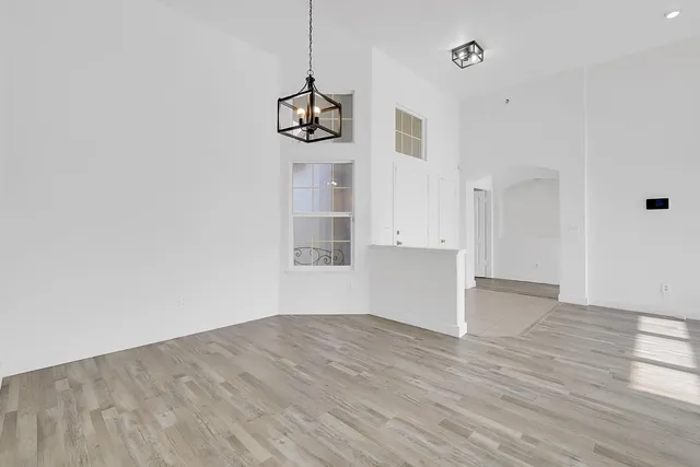 a view of an empty room with wooden floor and window