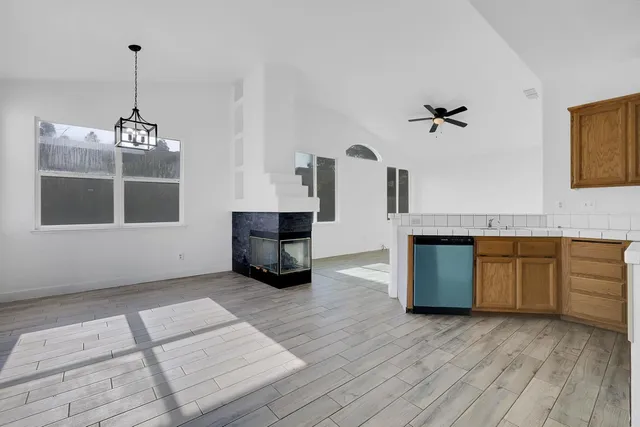 a living room with stainless steel appliances kitchen island granite countertop a stove a sink and a wooden floors