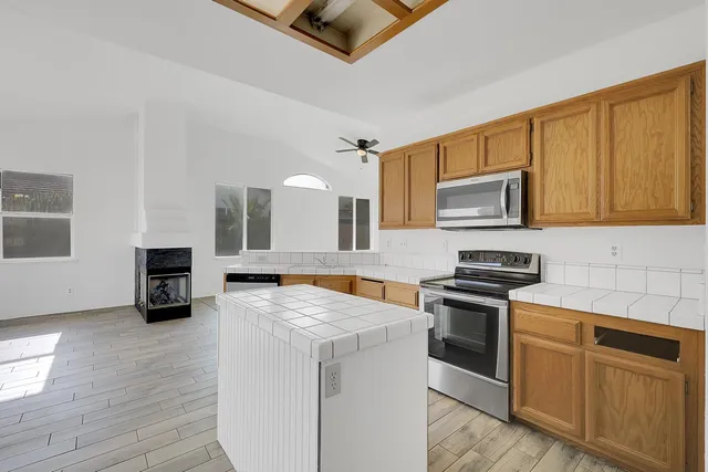 a kitchen with stainless steel appliances granite countertop a stove top oven a sink dishwasher and a microwave oven with wooden floor