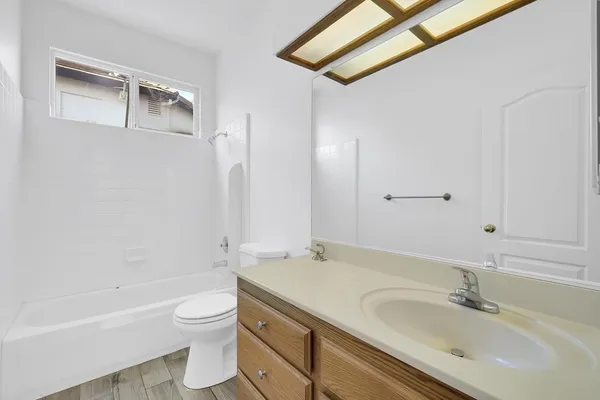 a bathroom with a granite countertop sink a toilet and bathtub
