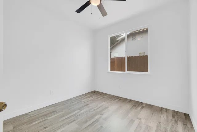 an empty room with a window and ceiling fan