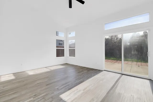 an empty room with wooden floor and windows