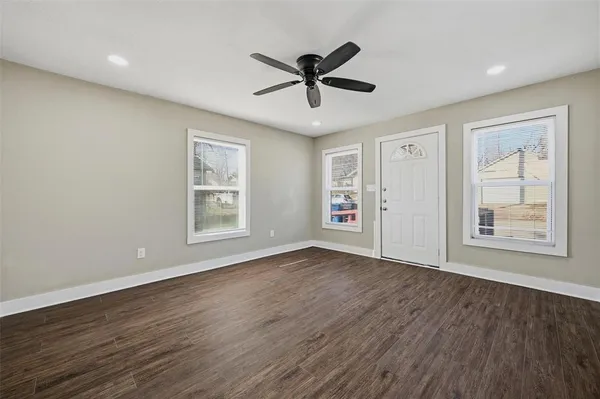 a view of an empty room with a window and wooden floor