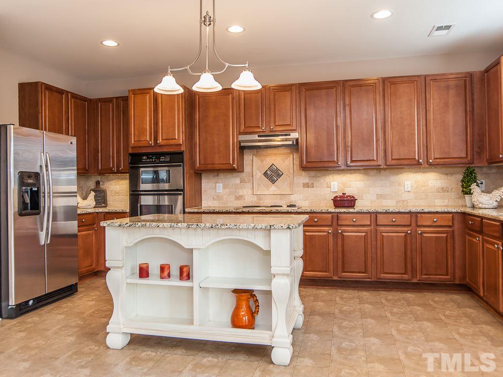 6040 Ricker Road Raleigh, NC 27610 - Photo 2 of 25 a kitchen with kitchen island granite countertop a stove cabinets and refrigerator