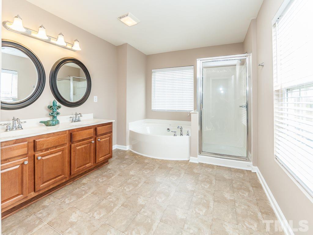 6040 Ricker Road Raleigh, NC 27610 - Photo 20 of 25 a spacious bathroom with a granite countertop double vanity sink a mirror and a bathtub