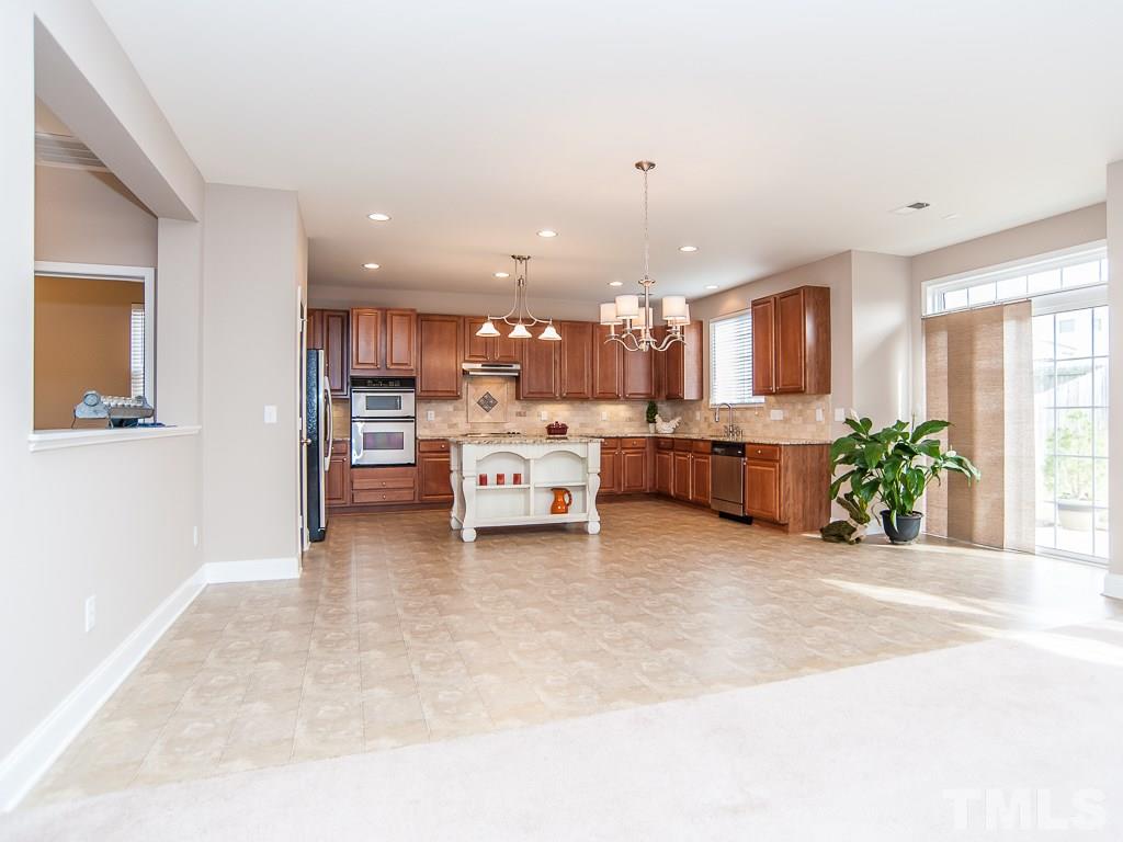6040 Ricker Road Raleigh, NC 27610 - Photo 8 of 25 a view of a kitchen with kitchen island a counter top space a sink stainless steel appliances and cabinets