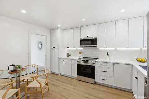 a kitchen with stainless steel appliances granite countertop a stove a sink dishwasher and a refrigerator with wooden floor